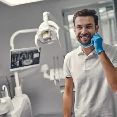 Uśmiechnięty dentysta w gabinecie, gotowy do pracy. Zastanawiasz się, ile trwa plombowanie zęba? Krótka wizyta i zdrowy uśmiech!