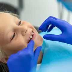 Uśmiechnięta dziewczynka z aparatem na diastemę, podczas wizyty u ortodonty.