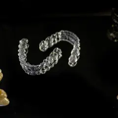 Przezroczyste nakładki Invisalign vs tradycyjny aparat ortodontyczny. Kamienie i kryształy na czarnym tle.