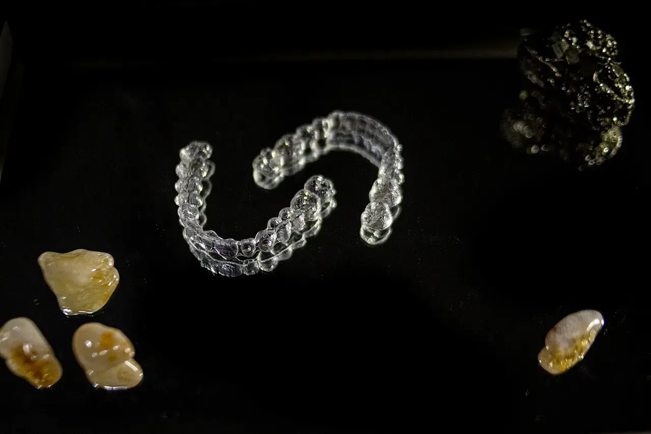 Przezroczyste nakładki Invisalign vs tradycyjny aparat ortodontyczny. Kamienie i kryształy na czarnym tle.