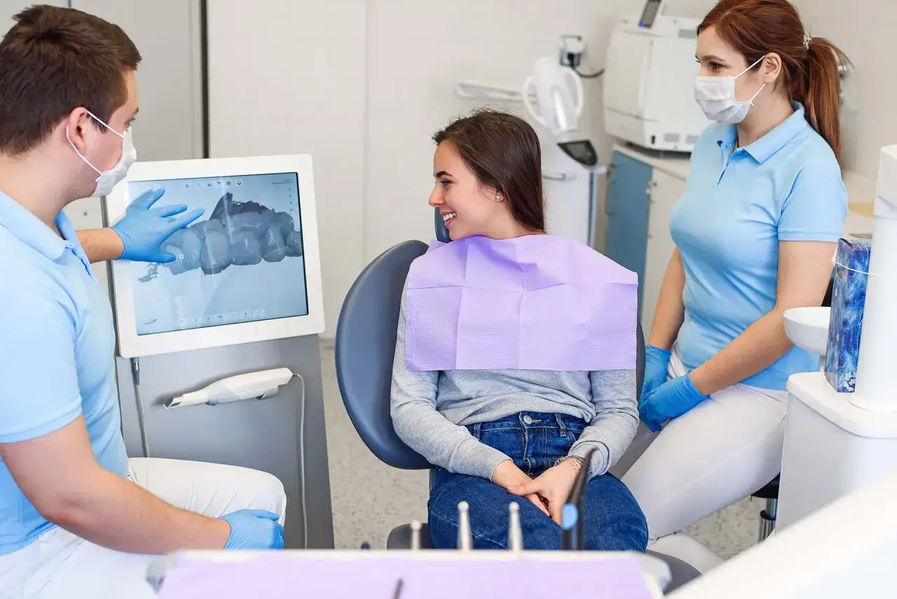 Dentysta omawia z pacjentką plan leczenia na ekranie, pokazując skan 3D zębów. To pierwszy krok, by dowiedzieć się, ile trwa założenie aparatu od pierwszej wizyty.